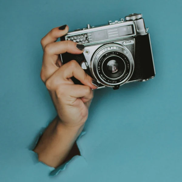 Une main avec un vieil appareil photo traverse un mur de papier